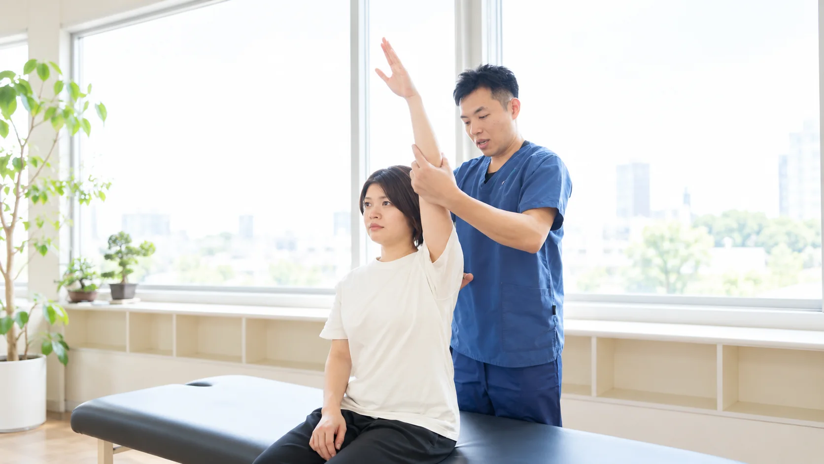 施術者が、腕を上げた女性の肩の動きを確かめている様子