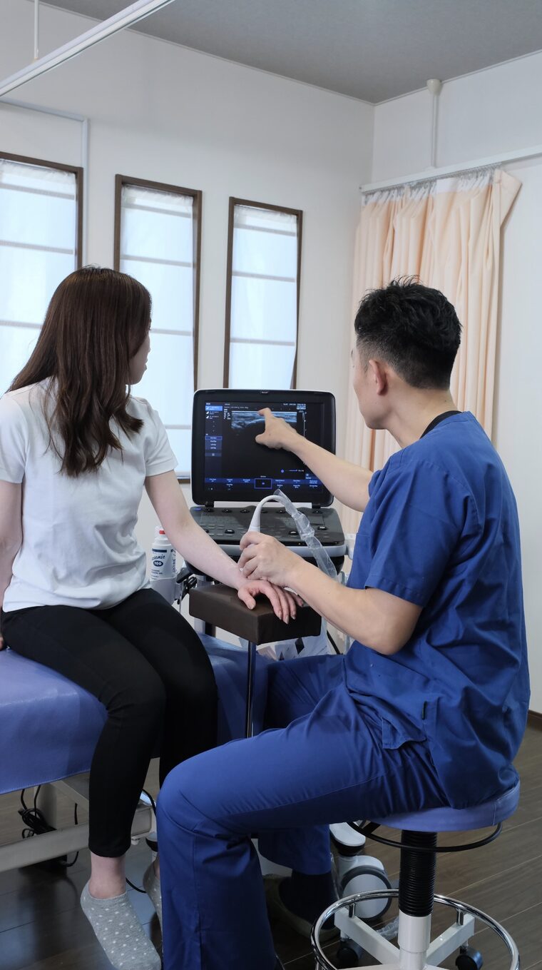 施術者が、エコーの画面を指し示しながら女性に説明している様子
