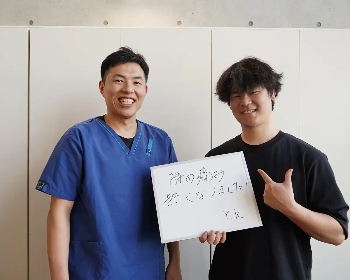 院長と来院された方が「腰の痛み無くなりました！」と書いた手書きボードを持つ写真